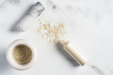 Ubtan natural face wash cosmetic preparation. Bowl with ubtan powder and beauty product bottle on marble desk. Flat lay, top view.