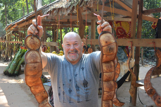 Smiling man holding two pods of Entada Rheedii