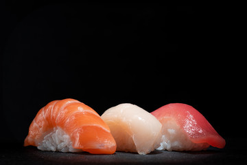 Japanese sushi set with salmon, tuna and perch on a black stone background, copy space © Andrey