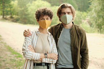 Happy young affectionate couple in protective handmade masks and casualwear