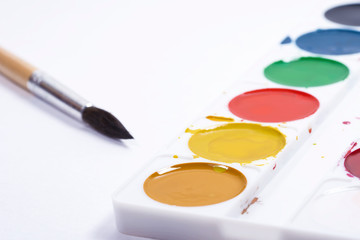 Colorful watercolor brush strokes, top view of paintbrushes palette and watercolor paints with white paper