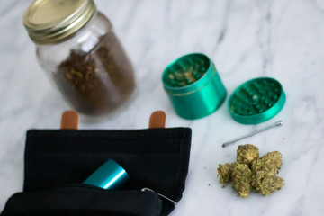 Cannabis kit with vaporizer and grinder on white marble.