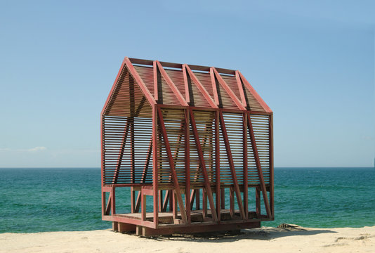 Estrutura de pequena casa constru&iacute;da em ripas de madeira perto do mar