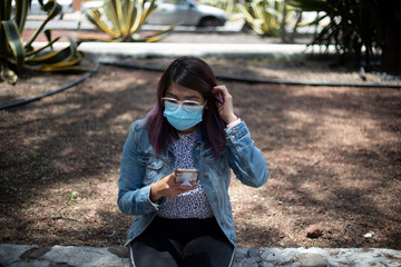 mujer con cubre bocas. llamada. pandemia. corona virus. celular. escribiendo
