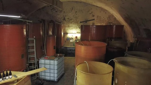 Drone flying within a cellar over multiple vats where the wine macerates