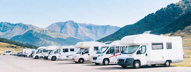 Summer tourism with RV. Campers parked in a row in a caravan parking area. Best option for travel in times of coronavirus pandemic. - obrazy, fototapety, plakaty