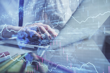 Double exposure of woman hands typing on computer and financial graph hologram drawing. Stock market analysis concept.