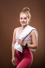 Blond fit woman in sportswear holding white soft towel while having short break