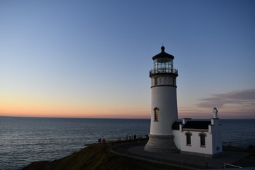 Lighthouse stands along coastal range at dusk.