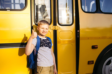 Happy boy in front of school bus. Back to school. Education. Day of knowledge.