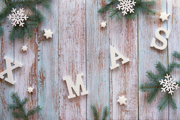 Creative Christmas flat lay with white letters Xmas on rustic wooden boards. Fir twigs decorated with wooden snowflakes and white star trinkets.