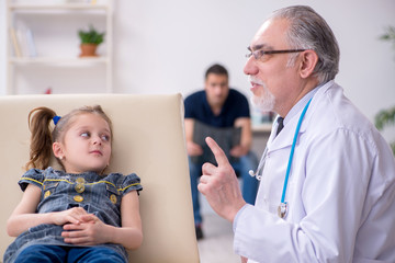 Young father and his daughter visiting old male doctor