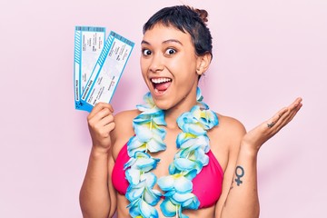 Young woman wearing bikini and hawaiian lei celebrating achievement with happy smile and winner...