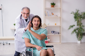 Fototapeta premium Young male patient in wheel-chair and experienced doctor traumatologist