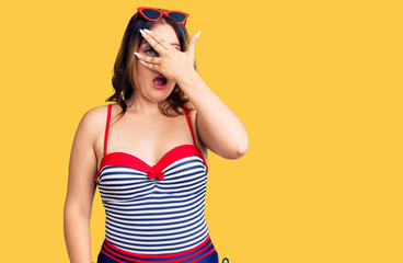 Young beautiful caucasian woman wearing swimwear peeking in shock covering face and eyes with hand, looking through fingers with embarrassed expression.