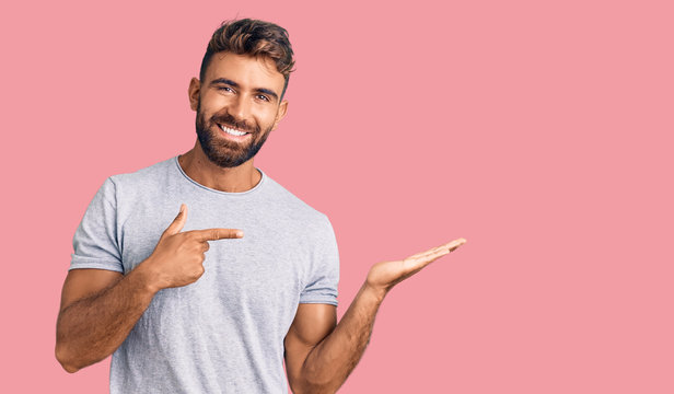 Young hispanic man wearing casual clothes amazed and smiling to the camera while presenting with hand and pointing with finger.