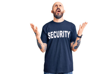 Fototapeta premium Young handsome man wearing security t shirt crazy and mad shouting and yelling with aggressive expression and arms raised. frustration concept.