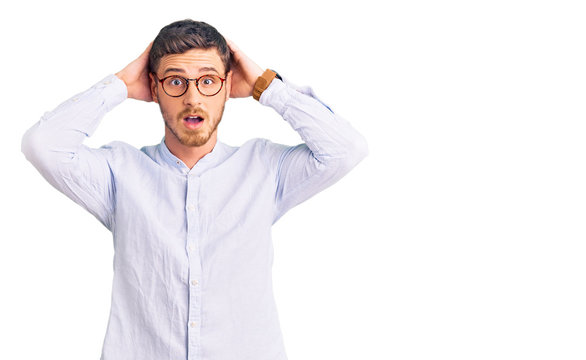 Handsome young man with bear wearing elegant business shirt and glasses crazy and scared with hands on head, afraid and surprised of shock with open mouth