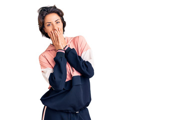 Young beautiful woman wearing sportswear laughing and embarrassed giggle covering mouth with hands,...