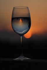 Reflection of the sun at sunset through a glass of wine.