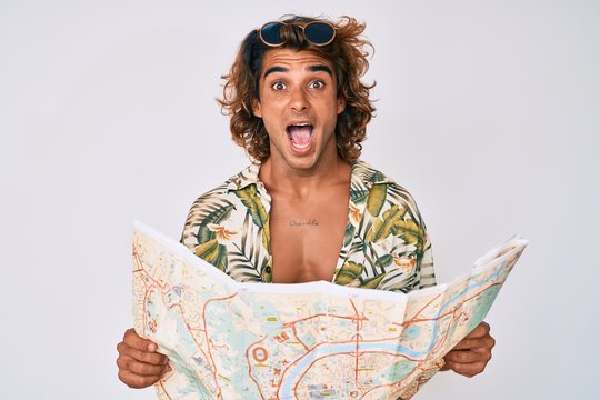 Young hispanic man wearing summer style holding map celebrating crazy and amazed for success with open eyes screaming excited.