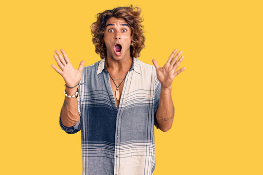 Young hispanic man wearing summer style celebrating crazy and amazed for success with arms raised and open eyes screaming excited. winner concept