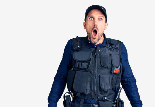 Young handsome man wearing police uniform afraid and shocked with surprise and amazed expression, fear and excited face.