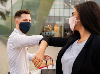 Two friends man and female saying hello with elbows on safe distance wearing masks 