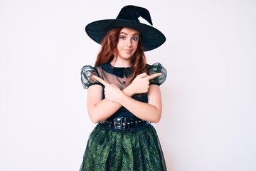 Young beautiful woman wearing witch halloween costume pointing to both sides with fingers, different direction disagree