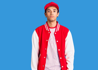 Young african amercian man wearing baseball uniform relaxed with serious expression on face. simple and natural looking at the camera.