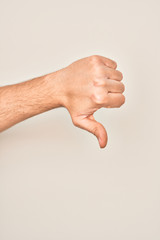 Hand of caucasian young man showing fingers over isolated white background doing thumbs down...