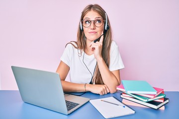 Young blonde girl wearing operator headset at the call center office thinking concentrated about...