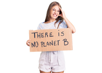 Young beautiful blonde woman holding there is no planet b banner stressed and frustrated with hand on head, surprised and angry face