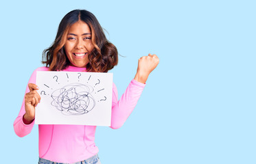 Young beautiful mixed race woman holding scribble draw screaming proud, celebrating victory and...