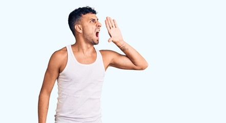 Young hispanic man wearing casual clothes shouting and screaming loud to side with hand on mouth....