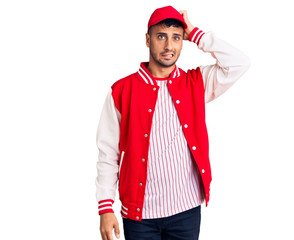 Young hispanic man wearing baseball uniform confuse and wonder about question. uncertain with doubt, thinking with hand on head. pensive concept.