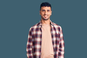 Young hispanic man wearing casual clothes looking positive and happy standing and smiling with a confident smile showing teeth