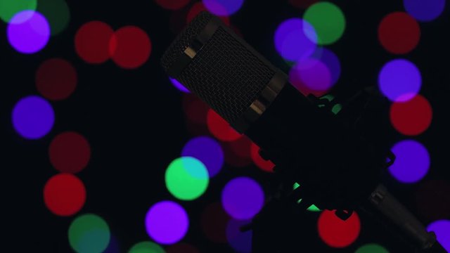 Micr&oacute;fono profesional de mesa con cable y montado en su base, con iluminaci&oacute;n din&aacute;mica y luces de colores en el fondo.