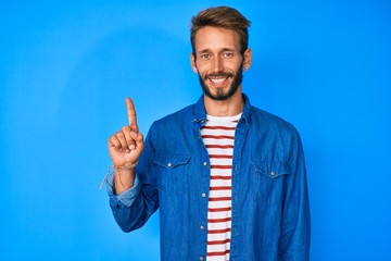 Handsome caucasian man with beard wearing casual clothes smiling with an idea or question pointing finger up with happy face, number one