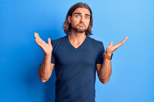 Young handsome man wearing casual clothes clueless and confused with open arms, no idea and doubtful face.