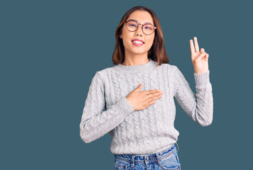Young beautiful chinese girl wearing casual clothes smiling swearing with hand on chest and fingers...
