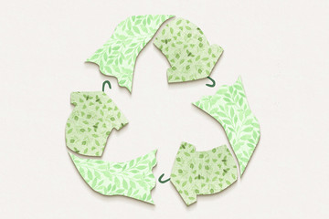 Recycle textiles symbol made from old clothing fabric on white recycled card background. Top view or flat lay. Reuse, reduce, recycle for sustainable fashion concept