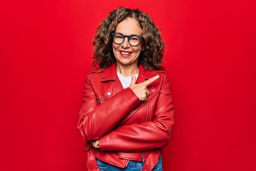 Middle age beautiful woman wearing casual red jacket and glasses over isolated background smiling...