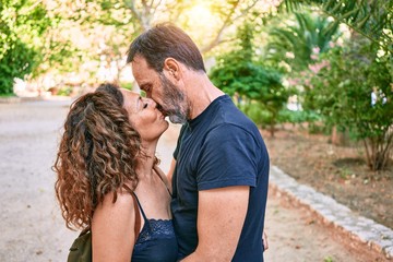 Middle age couple wearing casual clothes kissing at the forest