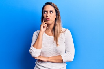 Young beautiful woman wearing casual t shirt thinking concentrated about doubt with finger on chin and looking up wondering