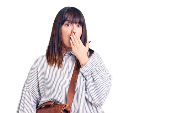 Young plus size woman wearing leather bag covering mouth with hand, shocked and afraid for mistake. surprised expression
