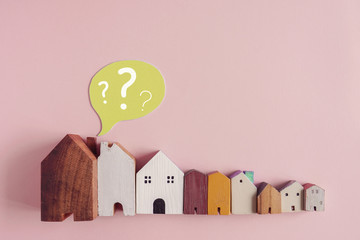 Wooden houses with question marks, housing crisis, confused decision, insecure investment, choosing...