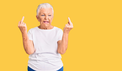 Senior beautiful woman with blue eyes and grey hair wearing casual white tshirt showing middle...