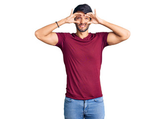 Fototapeta premium Handsome hispanic man wearing casual clothes trying to open eyes with fingers, sleepy and tired for morning fatigue
