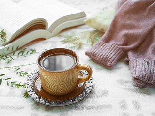 Fototapeta na wymiar Coffee in cup and Sweater with book on blanket background.